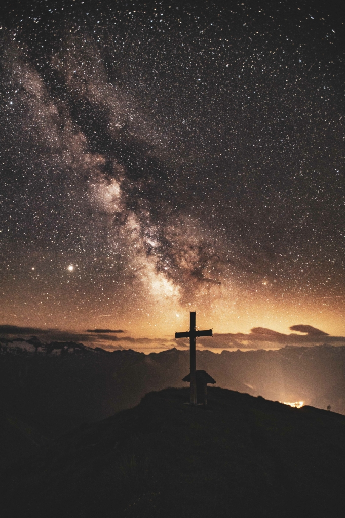 Sternenhimmel und Milchstraße über dem Gipfelkreuz am Gamskarkogel im Salzburger Land, Salzburg, Österreich.