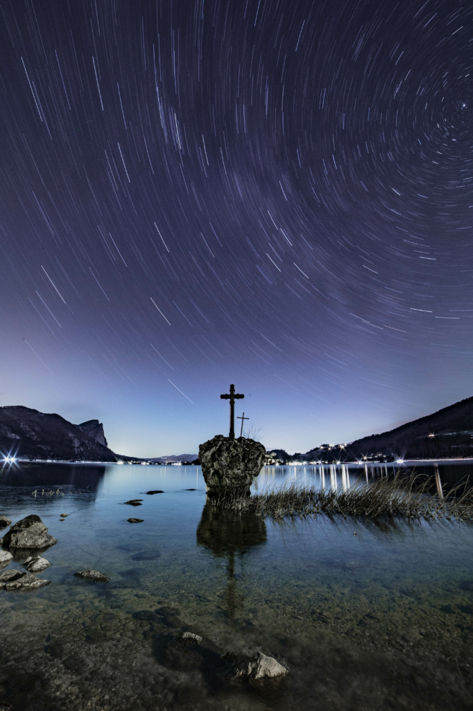 Sternenhimmel und Milchstraße über dem Kreuzstein im Mondsee and der Oberösterreichischen und Salzburger Grenze, Salzkammergut, Österreich.