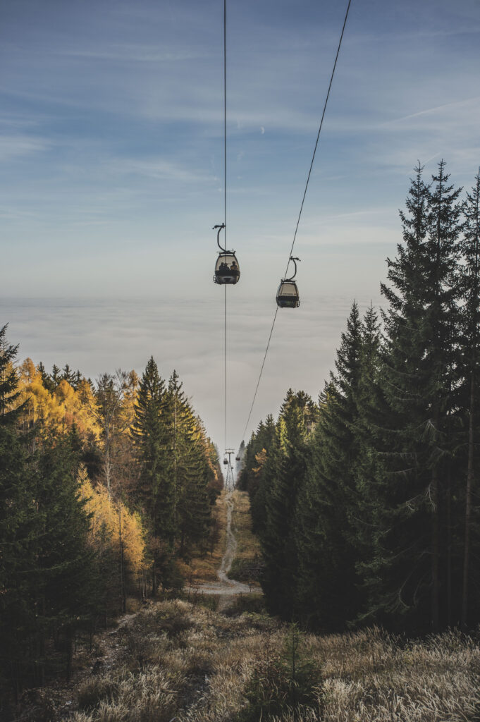 Die Gondeln der Schöckl-Seilbahn bahnen sich ihren Weg durch den herbstlichen Nebel in der Steiermark, Österreich.