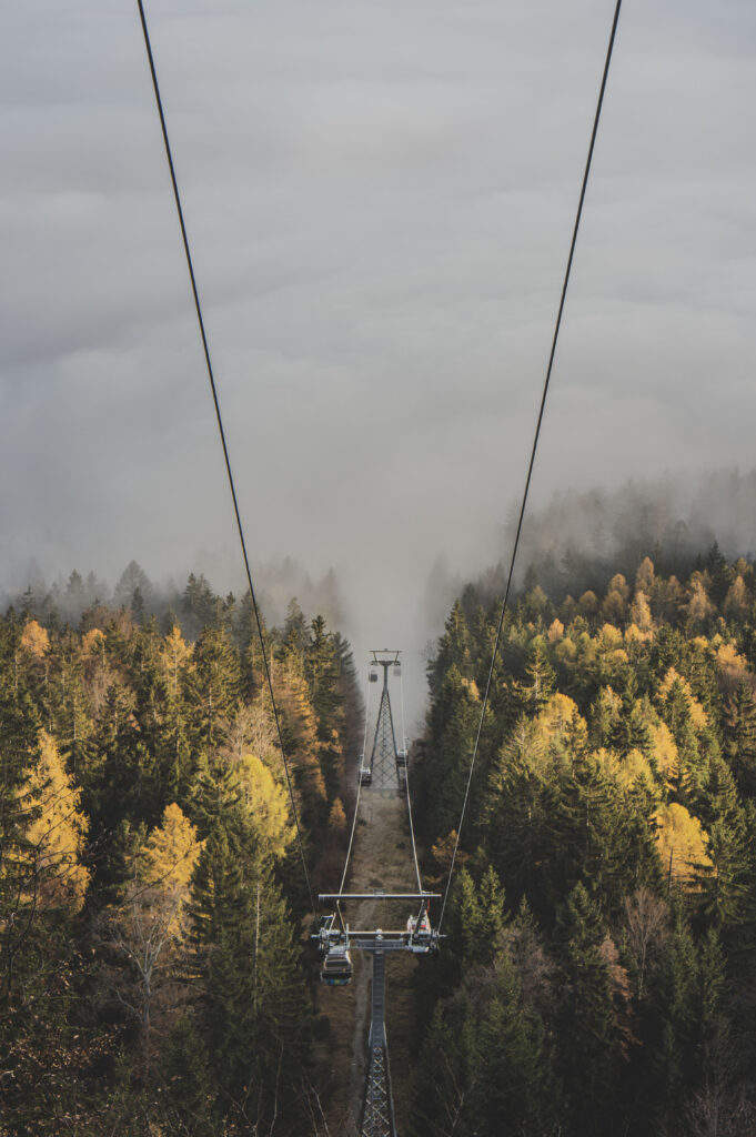 Die Gondeln der Schöckl-Seilbahn bahnen sich ihren Weg durch den herbstlichen Nebel in der Steiermark, Österreich.