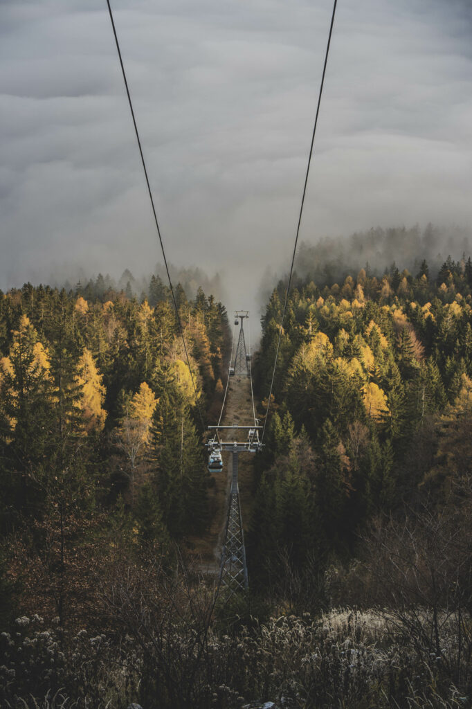 Die Gondeln der Schöckl-Seilbahn bahnen sich ihren Weg durch den herbstlichen Nebel in der Steiermark, Österreich.