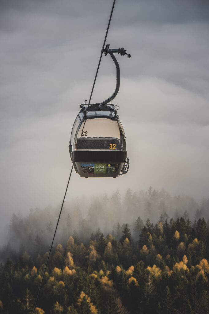 Die Gondeln der Schöckl-Seilbahn bahnen sich ihren Weg durch den herbstlichen Nebel in der Steiermark, Österreich.
