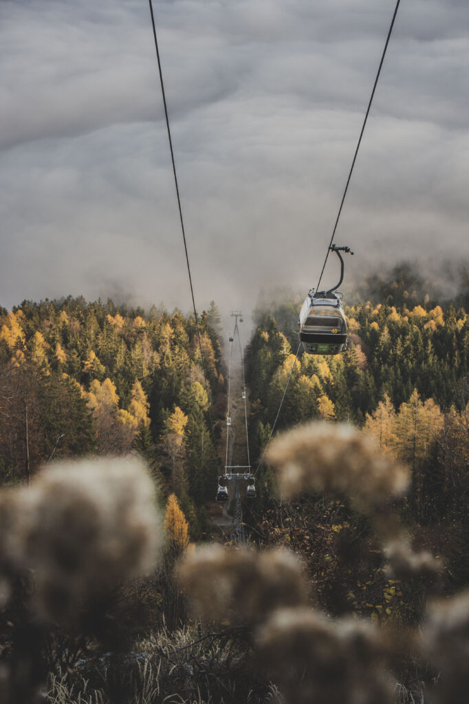 Die Gondeln der Schöckl-Seilbahn bahnen sich ihren Weg durch den herbstlichen Nebel in der Steiermark, Österreich.