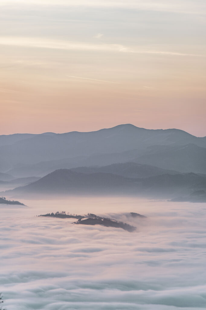 Nebeldecke über dem Grazer Bergland. Sonneuntergang am Gipfel des Grazer Hausberges Schöckl im Herbst, in der Steiermark, Österreich.