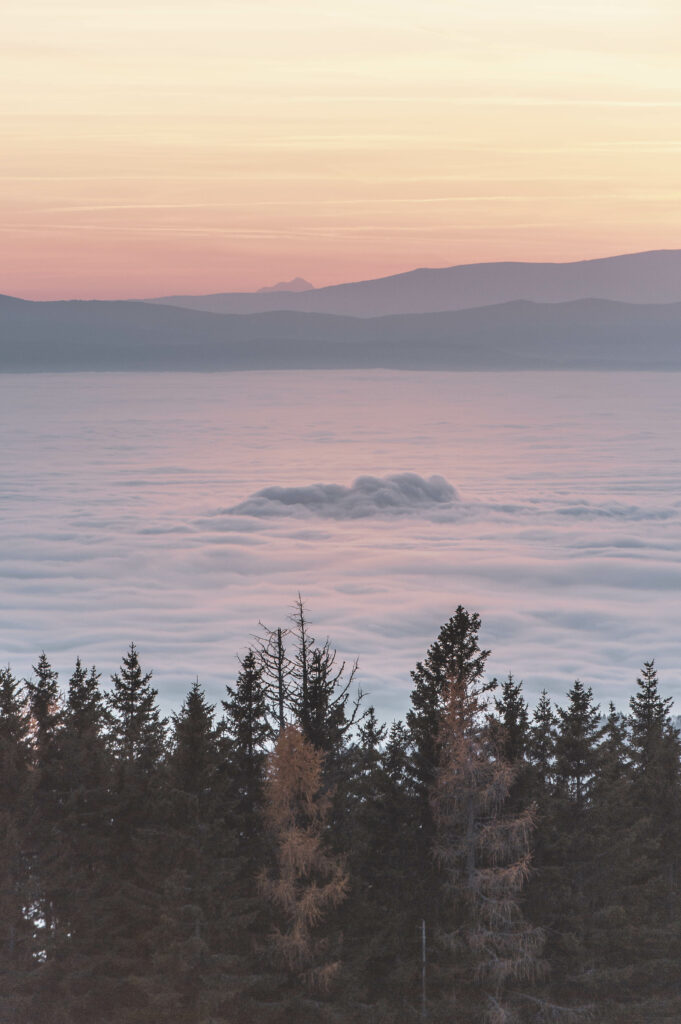 Nebeldecke über dem Grazer Bergland. Sonneuntergang am Gipfel des Grazer Hausberges Schöckl im Herbst, in der Steiermark, Österreich.