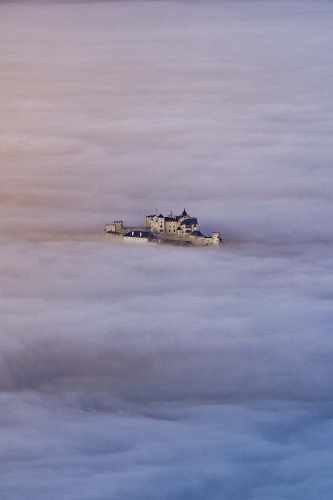 Die Festung Hohensalzburg ragt aus dem Morgennebel. Fotografiert vom Gaisberg, Salzburg Land, Österreich.