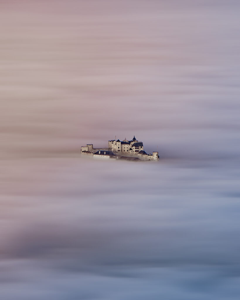 Die Festung Hohensalzburg ragt aus dem Morgennebel. Fotografiert vom Gaisberg, Salzburg Land, Österreich.