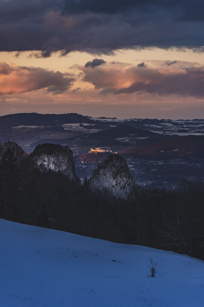 Sonnenuntergang und Blick auf die Stadt Salzburgvon Bad Dürrnberg, mit den Barmsteinen vor Hallein und der Festung Hohensalzburg am Horizont.